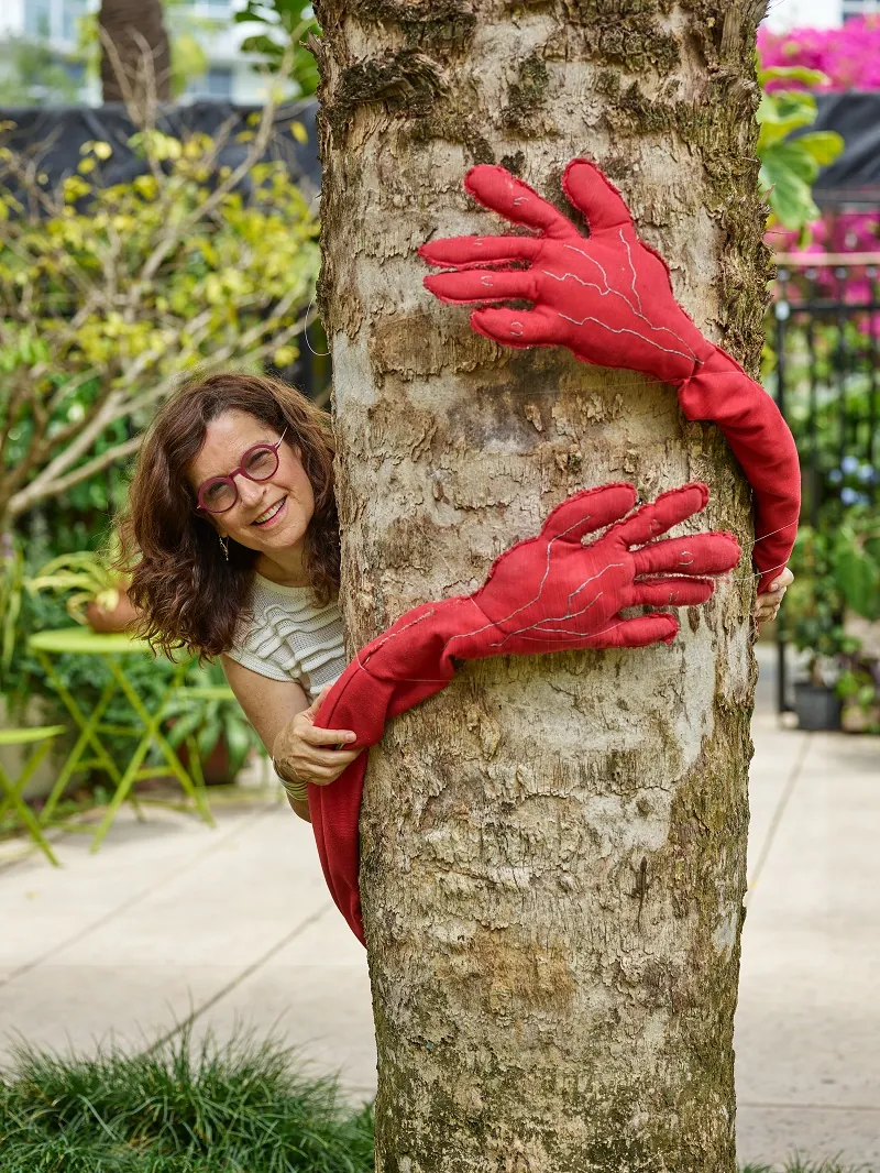 Evelyn hugging palm tree wrapped in fiber art