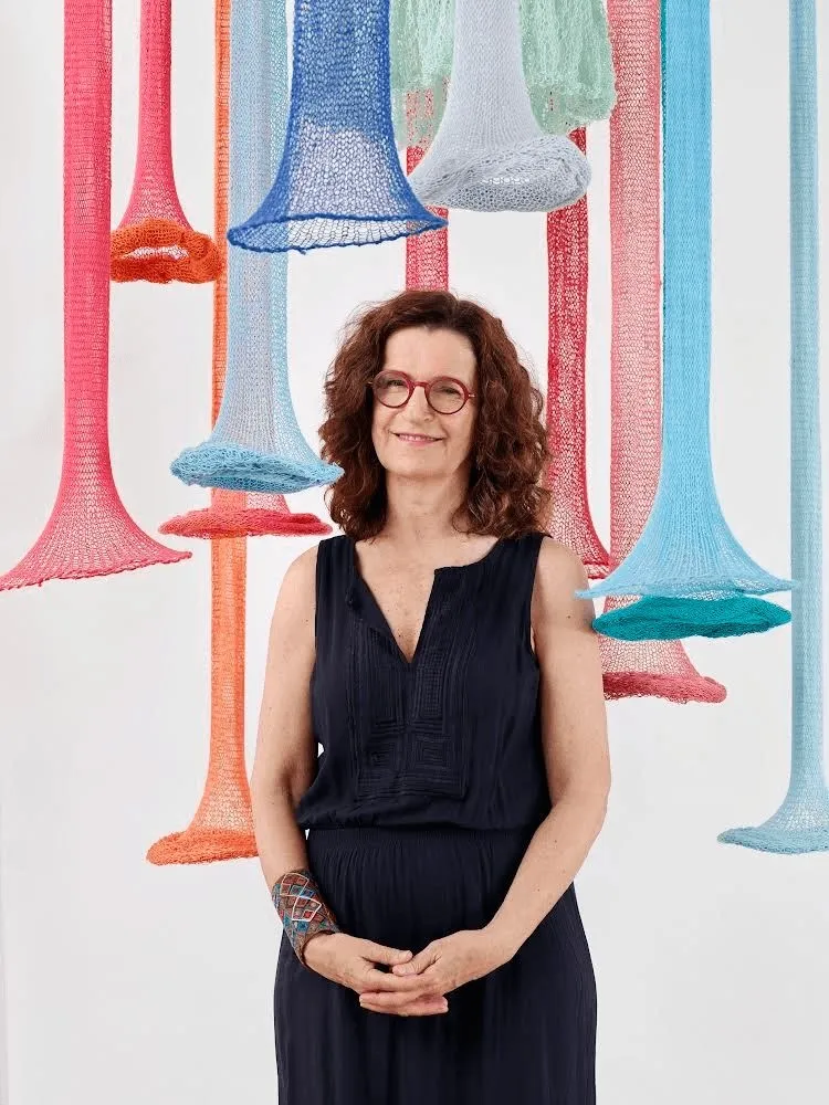 Evelyn Politzer standing in front of colorful, vertical knitted funnels - Shoutout Miami Interview