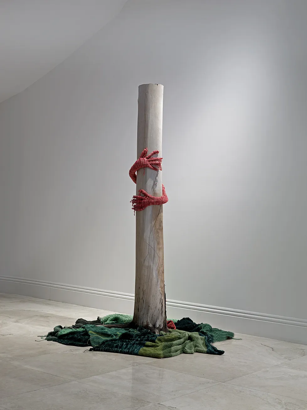 "Worth Holding on to" 2018. 7' x 3.5' x 3'. Rainbow eucalyptus tree trunk with silky merino hand knit hands and grass.